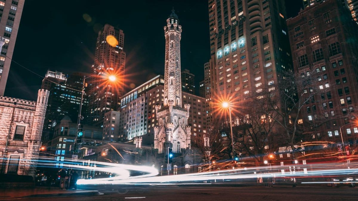 A stunning view of Chicago's historic Water Tower surrounded by skyscrapers, captured at night with vibrant city lights.