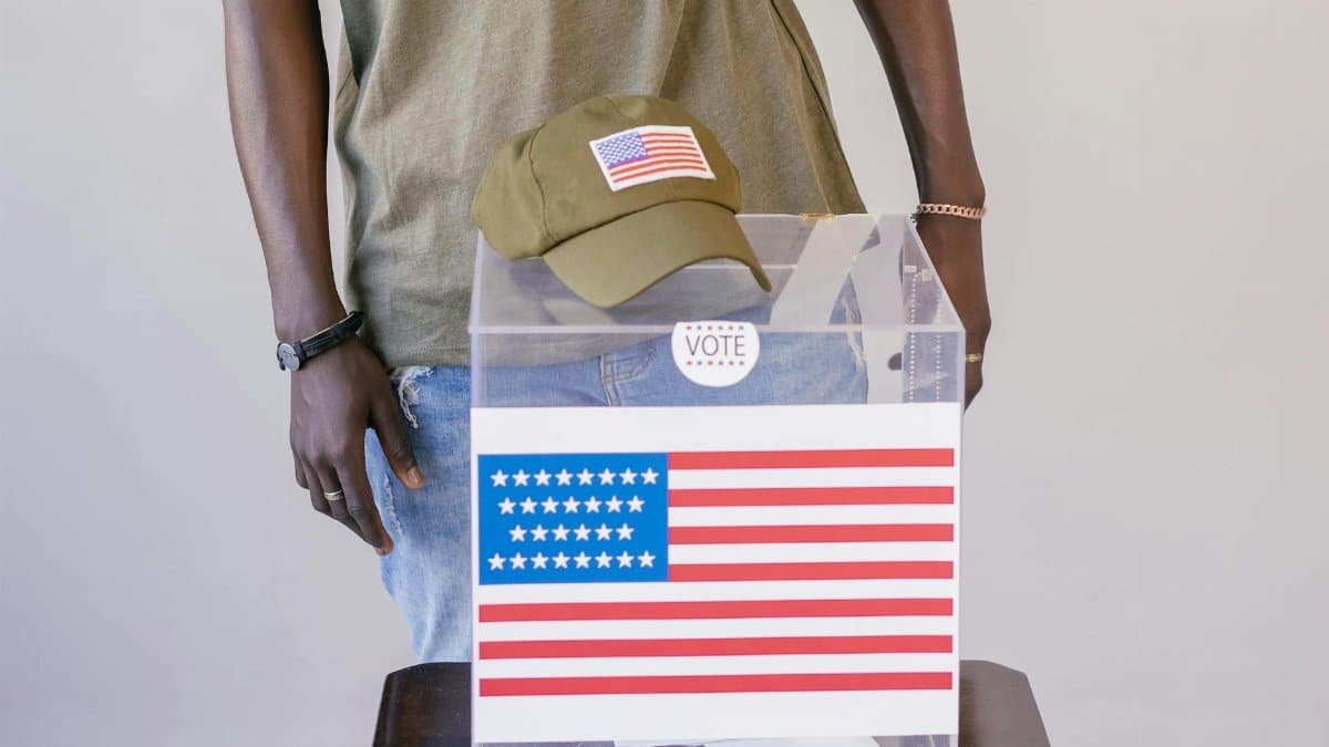 Adult voter standing by a ballot box with American flag, symbolizing democracy and election participation.