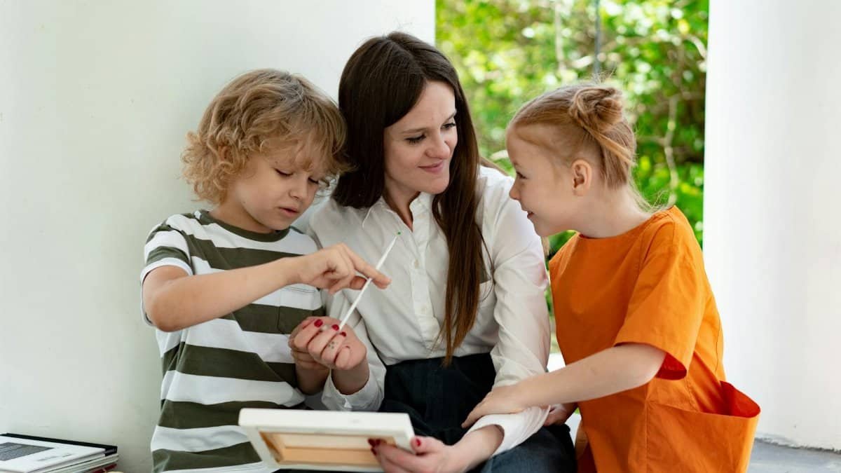 A loving mother engaging with her children in an outdoor painting activity, fostering creativity and bonding.