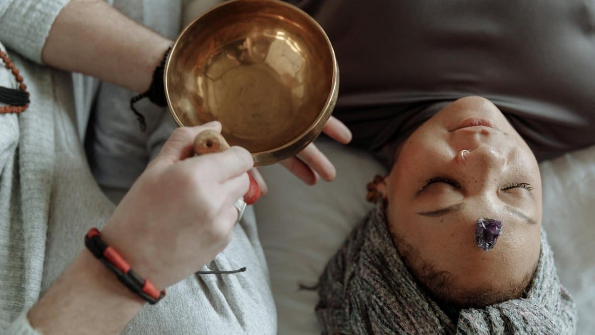 Woman receiving healing therapy with a Tibetan singing bowl placed during meditation.
