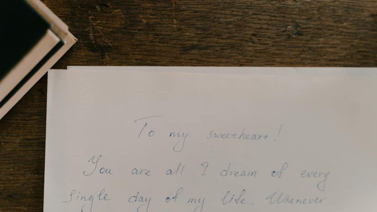 A heartfelt handwritten letter on paper placed on a wooden table.