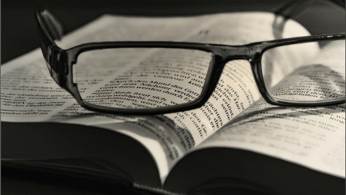 Artistic black and white image of eyeglasses resting on an open book. Ideal for literature or vision concepts.