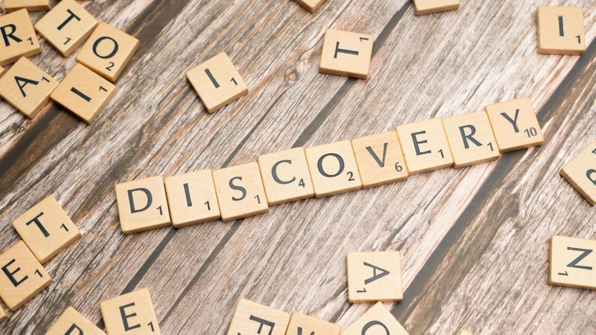 Close-up of wooden letter tiles on a table spelling 'Discovery', representing exploration and creativity.