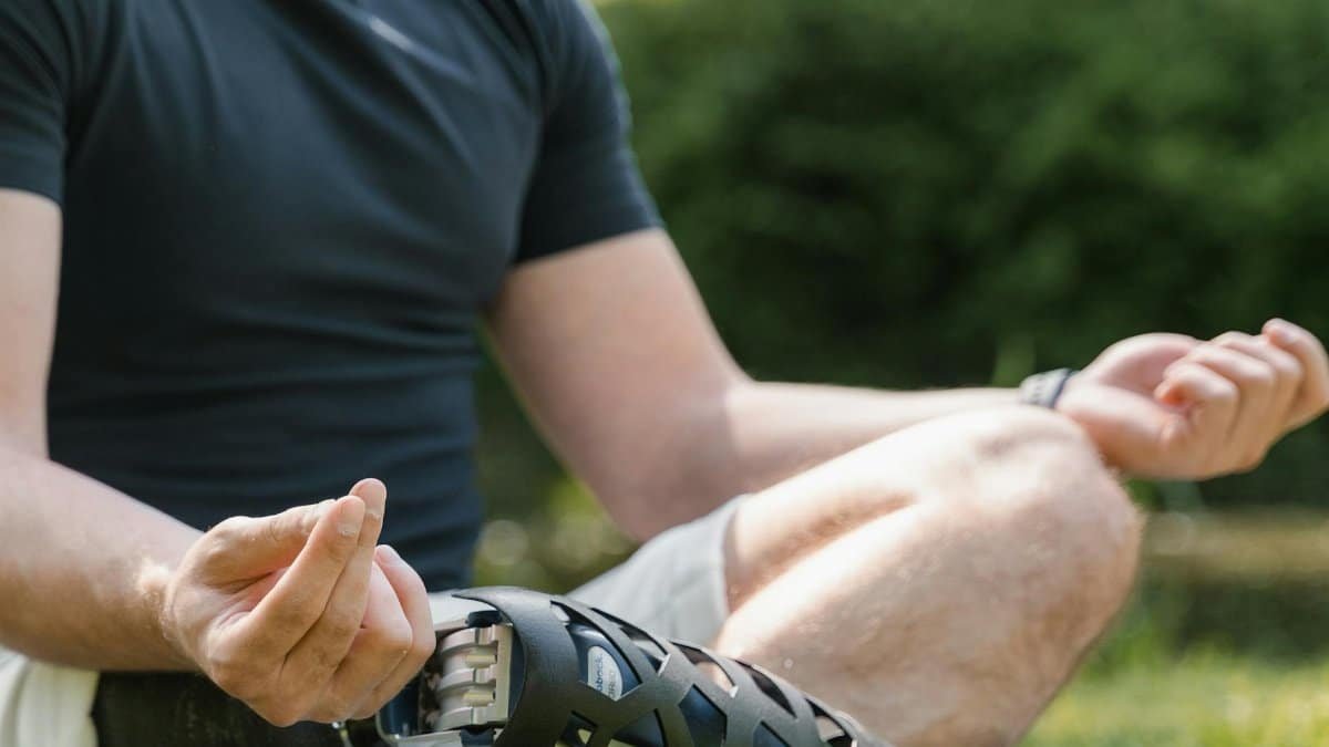 A person meditating in a park with a prosthetic leg, focusing on mindfulness and serenity.