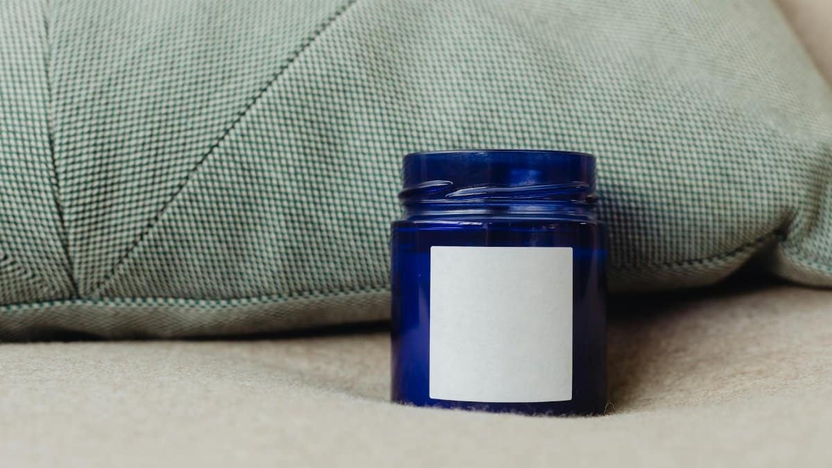 A blue container with a blank label, perfect for product mockups, against a cozy cushion backdrop.