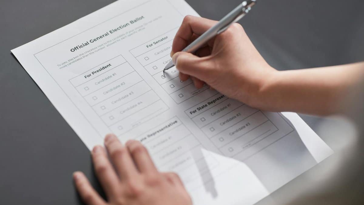 A close-up image of a hand marking an official election ballot with a pen, representing democratic voting.