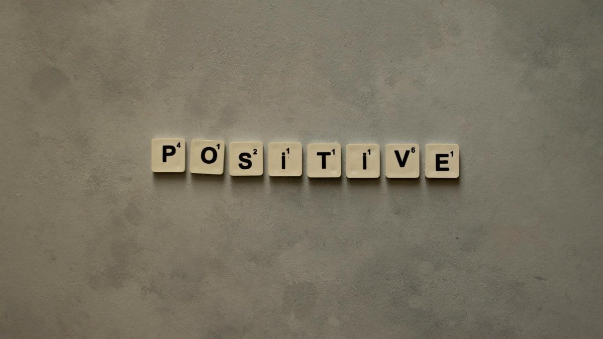 Scrabble tiles spelling 'Positive' on a textured surface, conveying optimism.