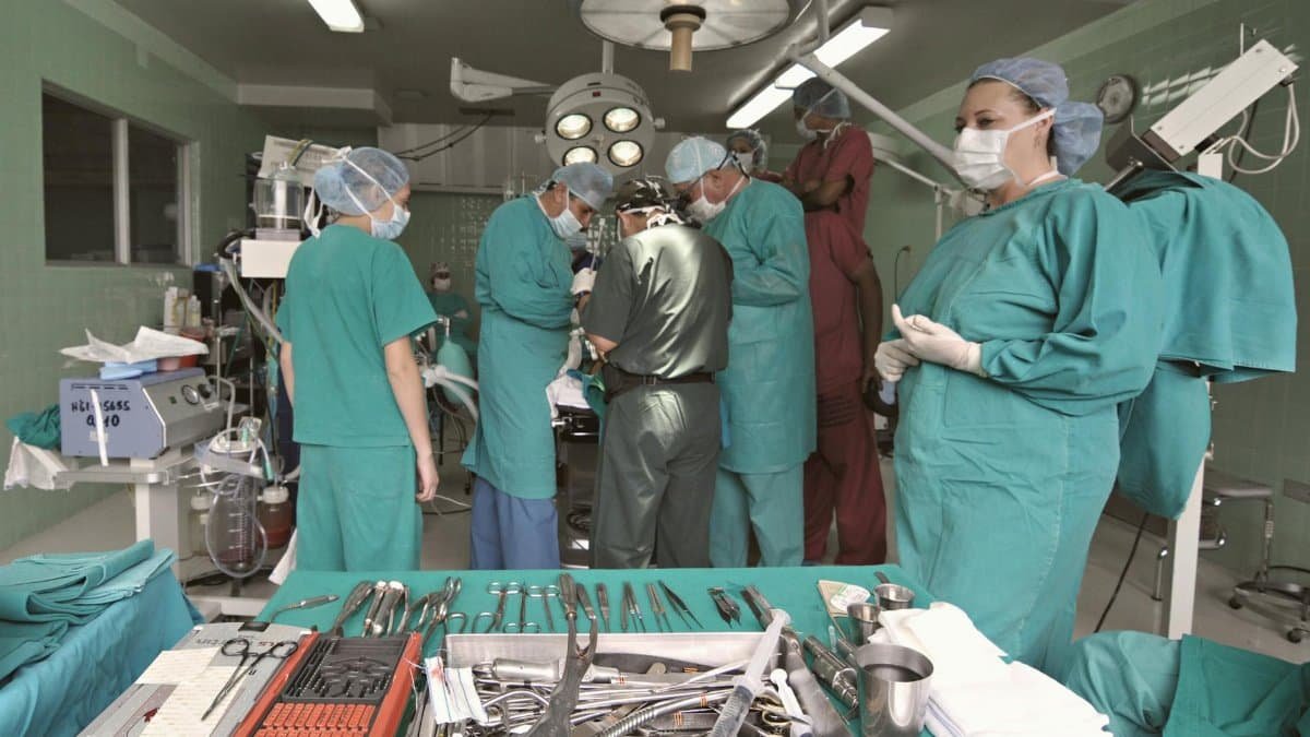 Medical team conducting surgery in a sterile operating room with surgical tools on display.