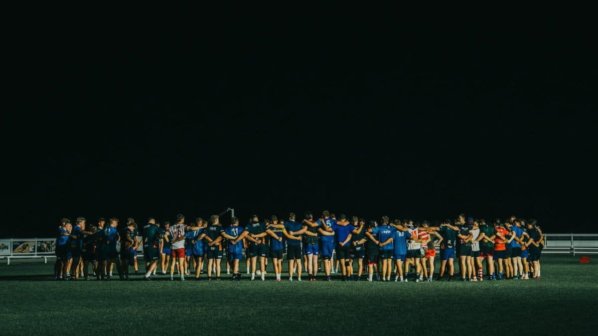 Sports team huddle on a field at night, fostering teamwork and unity.