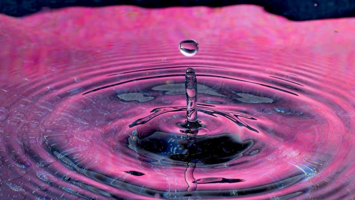 High-speed photo of vibrant water droplet creating colorful ripple effect.