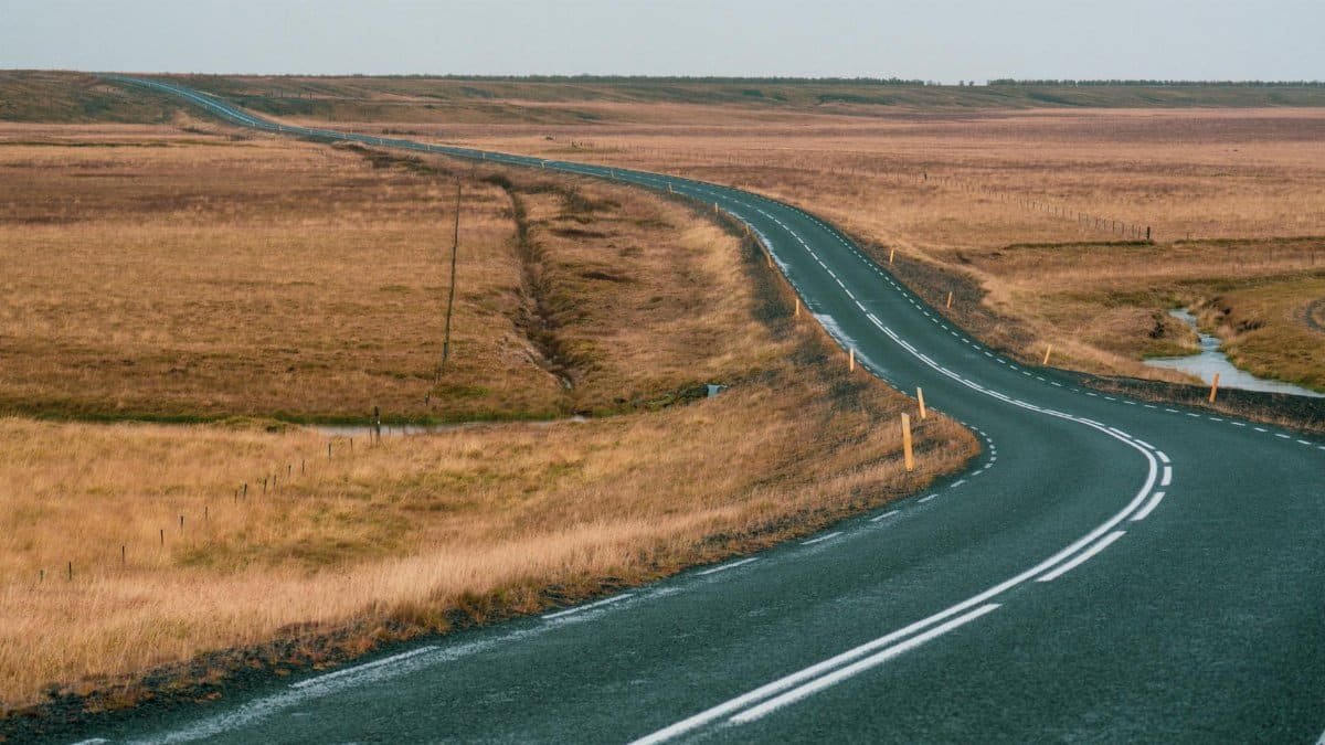 A scenic winding road through vast autumn plains under a clear sky, perfect for travel inspiration.