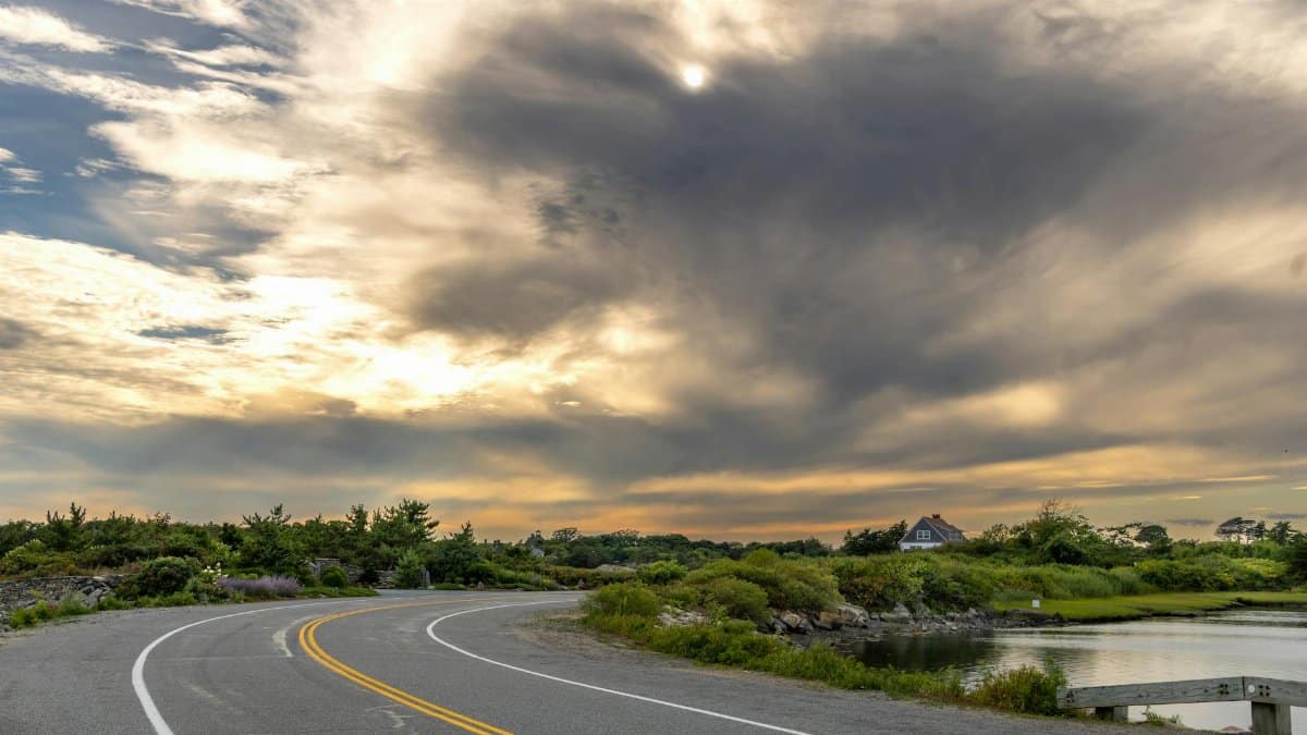 A peaceful road in New Shoreham, Rhode Island, with dramatic cloudy skies during sunset.