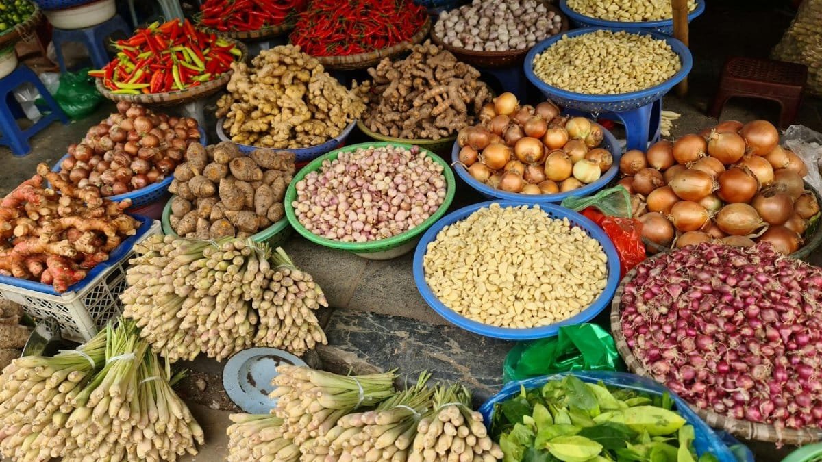 Colorful display of fresh vegetables and spices at a local market in Hanoi, Vietnam.