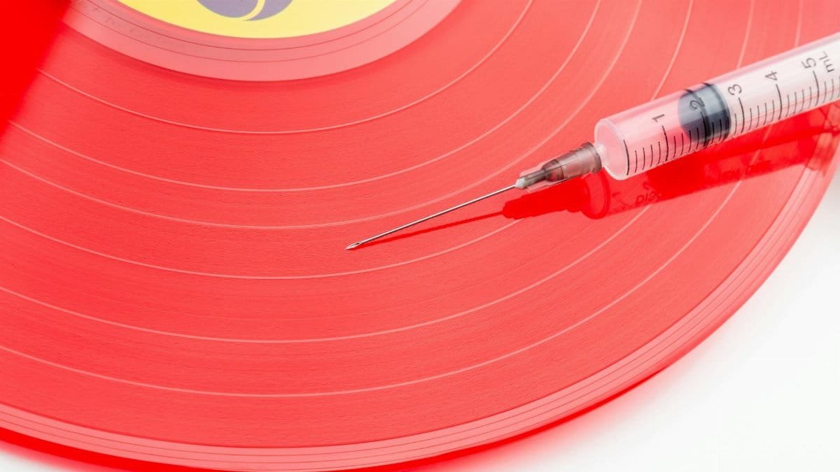 Conceptual image of a red vinyl record with a syringe symbolizing music addiction or nostalgia.