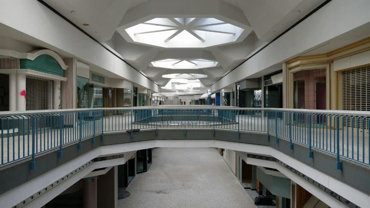 Abandoned shopping mall interior with closed stores and modern architecture.