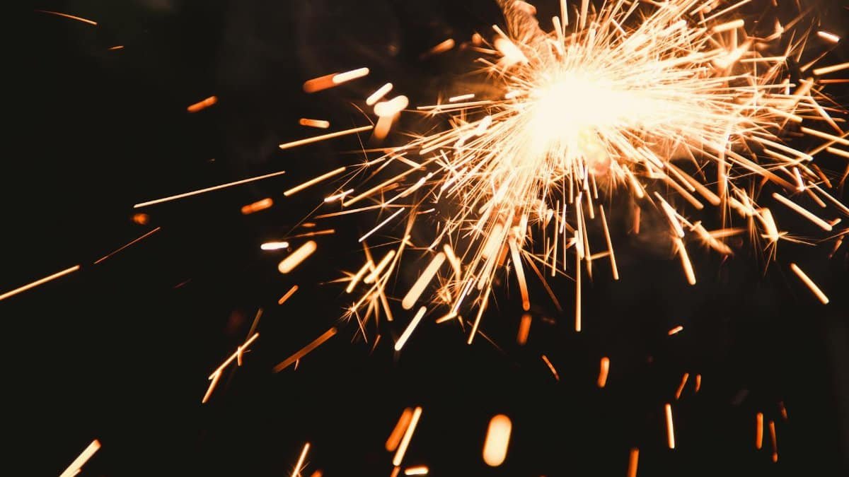 Vibrant sparkler emitting bright sparks in a close-up view, perfect for celebrations.