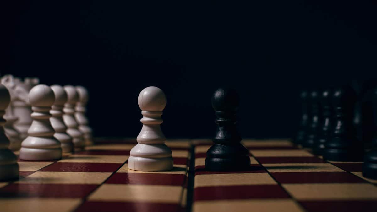 Close-up of chess pawns on a board in a strategic setup, capturing the essence of competition.