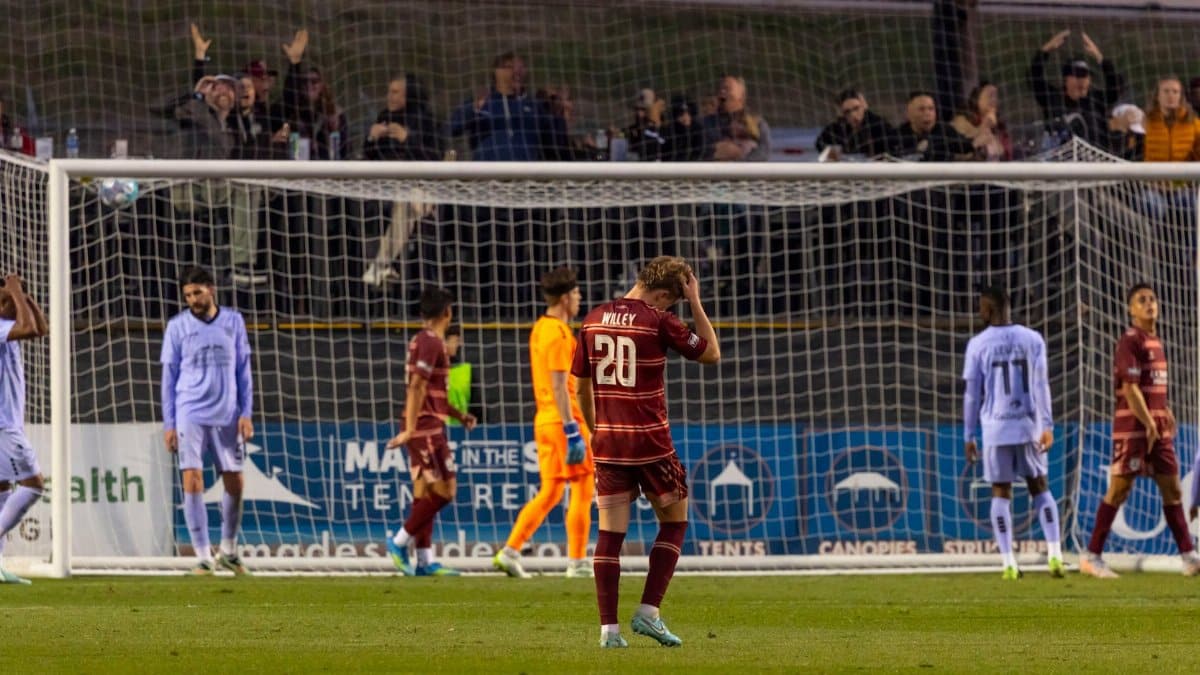 Soccer players express disappointment after missing a goal during a night match.