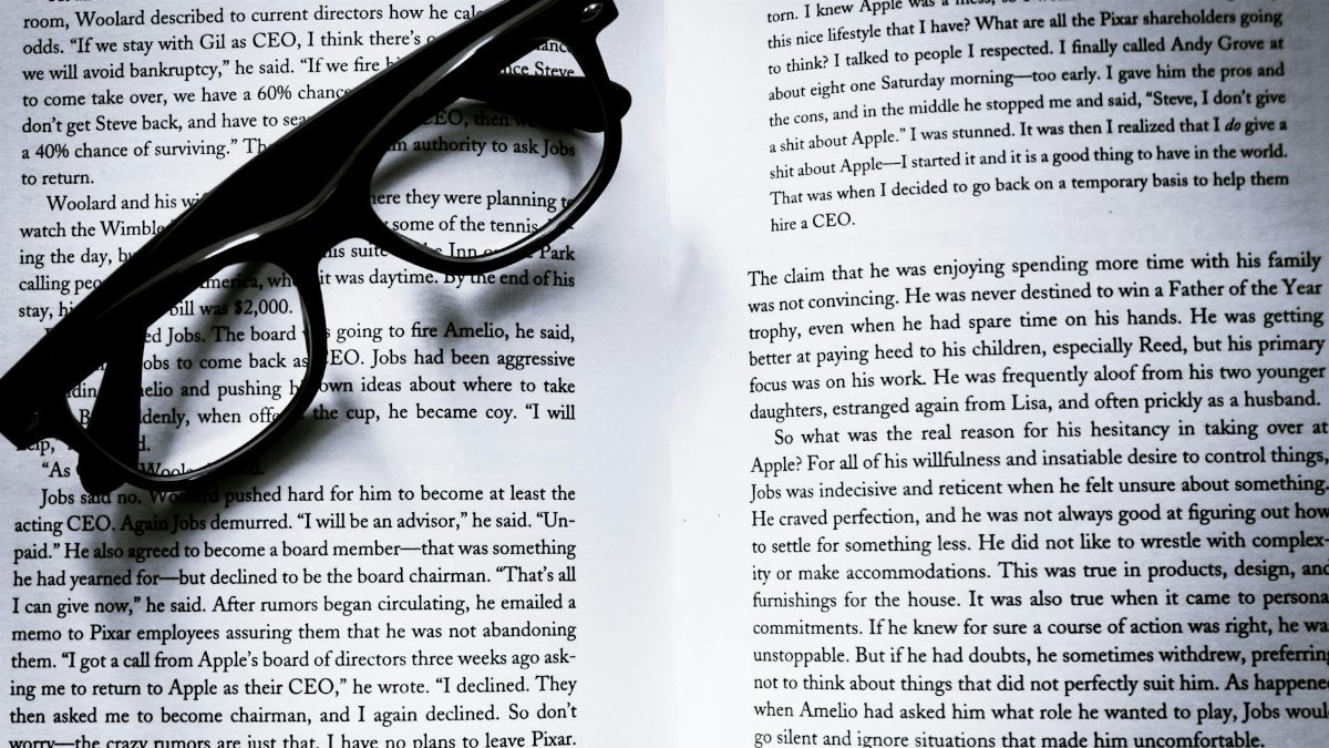 Black eyeglasses on open book pages with visible text, ideal for study themes.