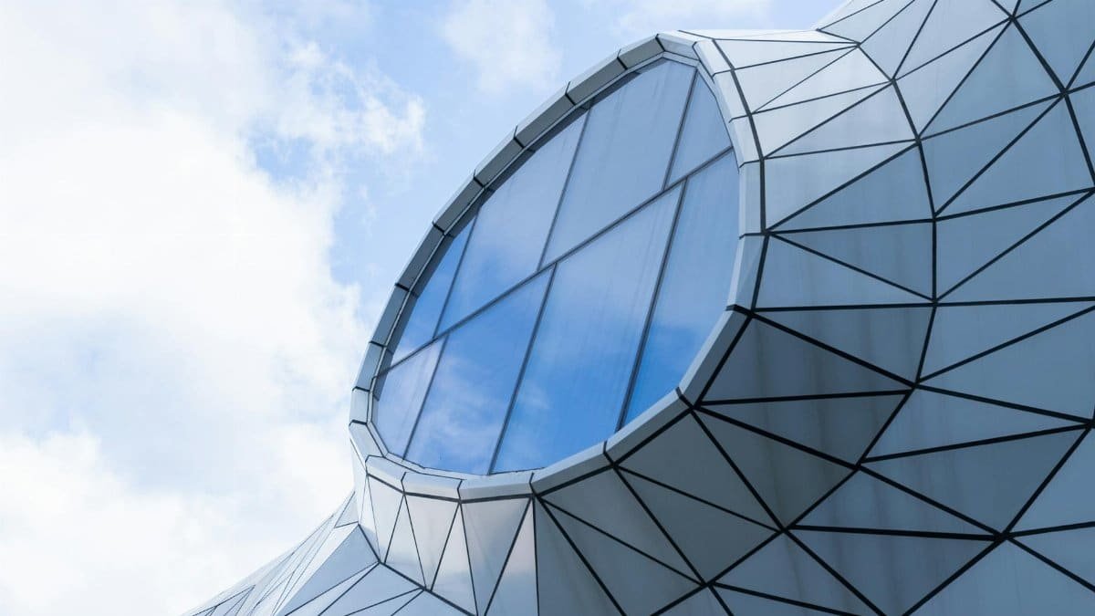 Modern, geometric architectural structure with a unique window design under a bright blue sky.