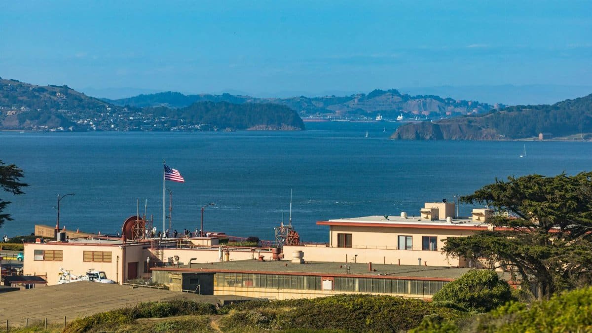 Aerial view of a harbor facility with an American flag, overlooking a serene bay area.
