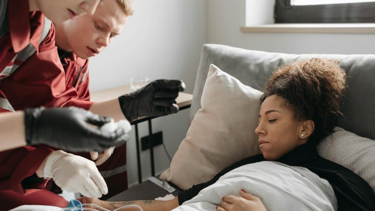 Paramedics providing medical care to a sick woman at home, illustrating healthcare and emergency support.