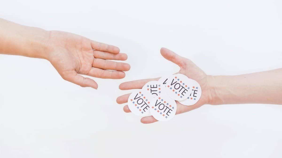 Close-up of hands exchanging vote stickers, symbolizing engagement in democratic election.