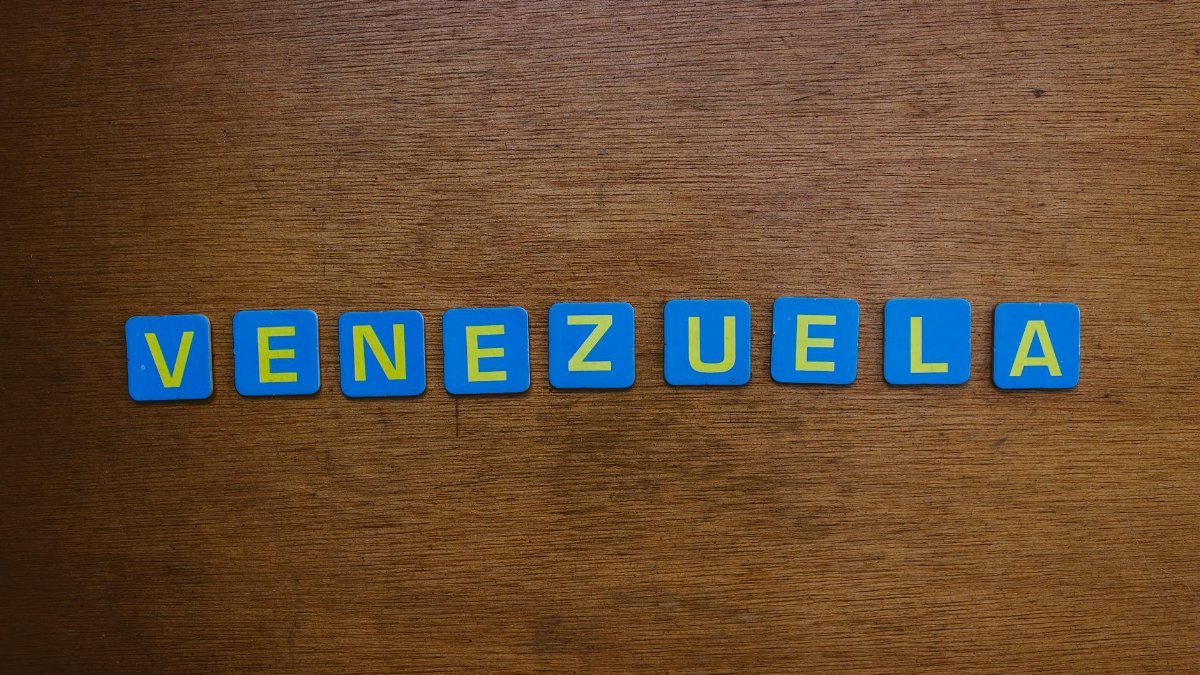 Blue and yellow letter tiles spelling Venezuela on a wooden surface.