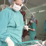 Surgeons and nurses in an operating room preparing for surgery with medical tools.