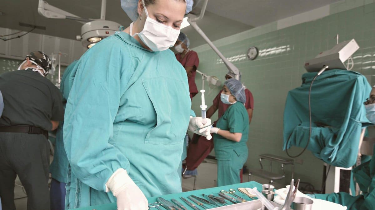 Surgeons and nurses in an operating room preparing for surgery with medical tools.