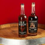 Two Ole Bison bourbon bottles on a barrel against a red background in New Orleans.