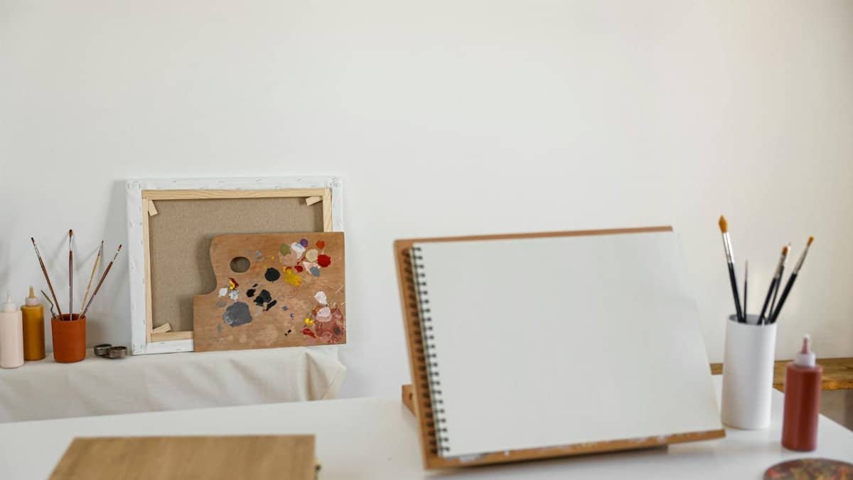 Cozy art studio setup with canvas, painting supplies, and blank notebook ready for creativity.