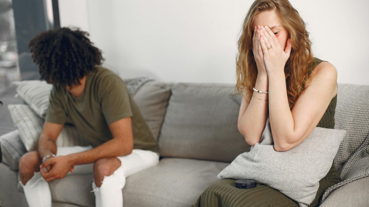 Couple experiencing emotional conflict on a sofa indoors with depth of field effect.