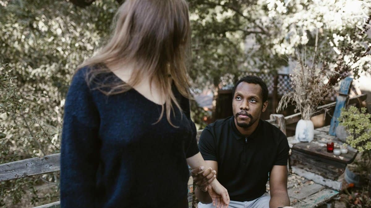A couple in a serious discussion outdoors, surrounded by nature.