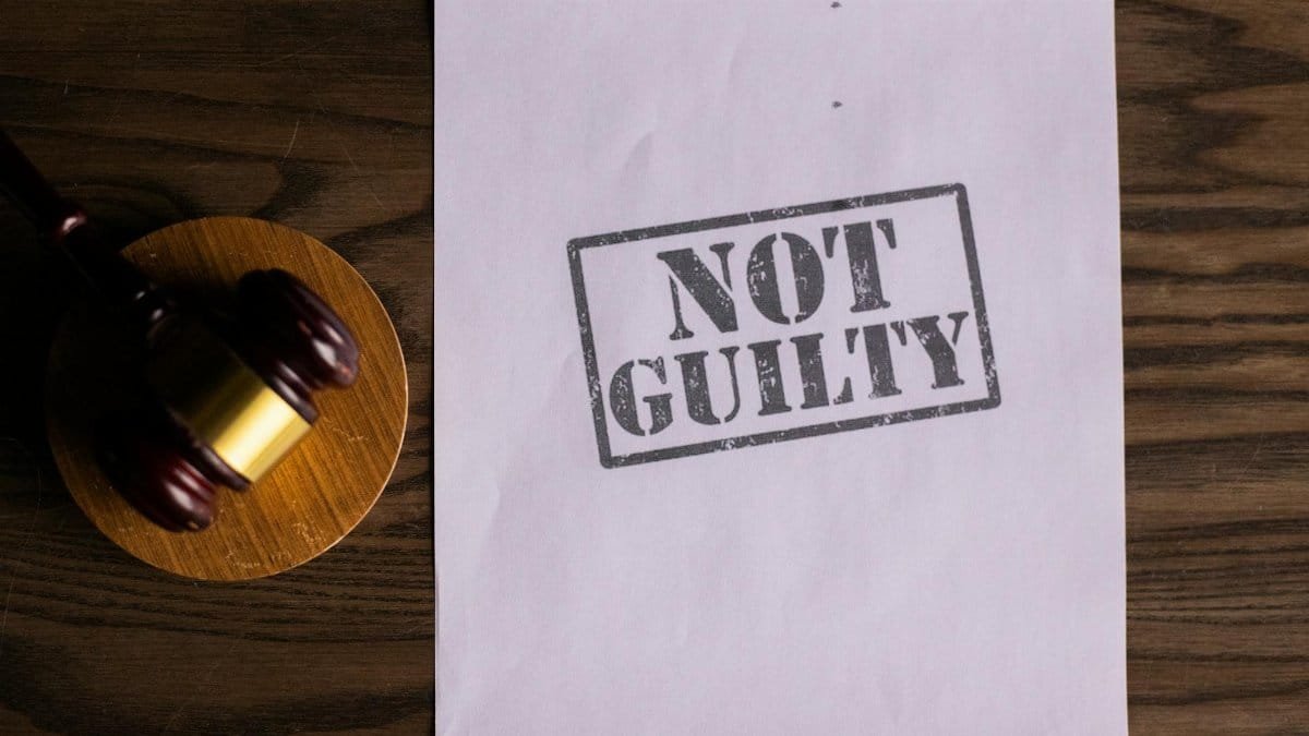 A courtroom document labeled 'Not Guilty' beside a gavel symbolizes justice.