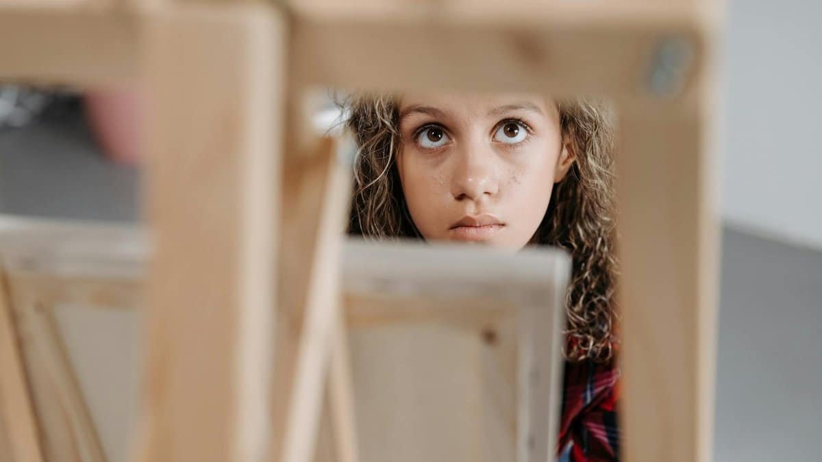 Curious young girl in an art class focused on a canvas, capturing creativity and concentration.