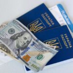 Close-up view of Ukrainian passports with US dollar bills, symbolizing travel readiness.