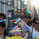 A vibrant street protest in Venezuela, showcasing joyous participants holding a political figure's portrait amid flags and smiles.