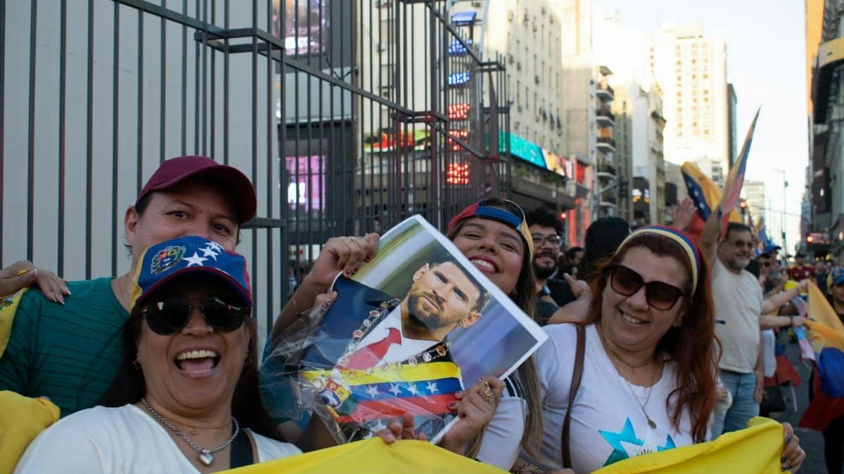 A vibrant street protest in Venezuela, showcasing joyous participants holding a political figure's portrait amid flags and smiles.