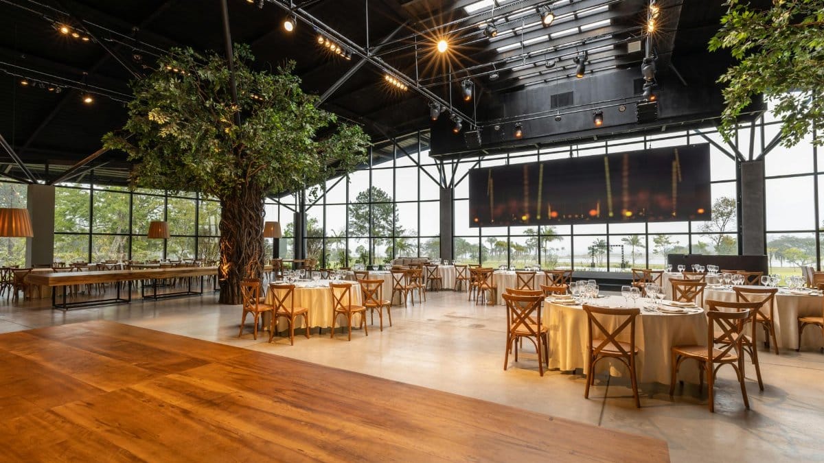 Spacious and elegant banquet hall with indoor trees, modern decor, and large windows for events or gatherings.