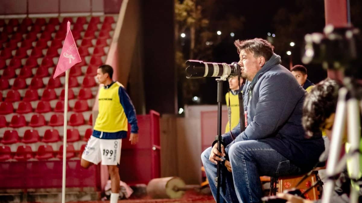 Soccer coach intensely watches game at night stadium, focused on strategy.