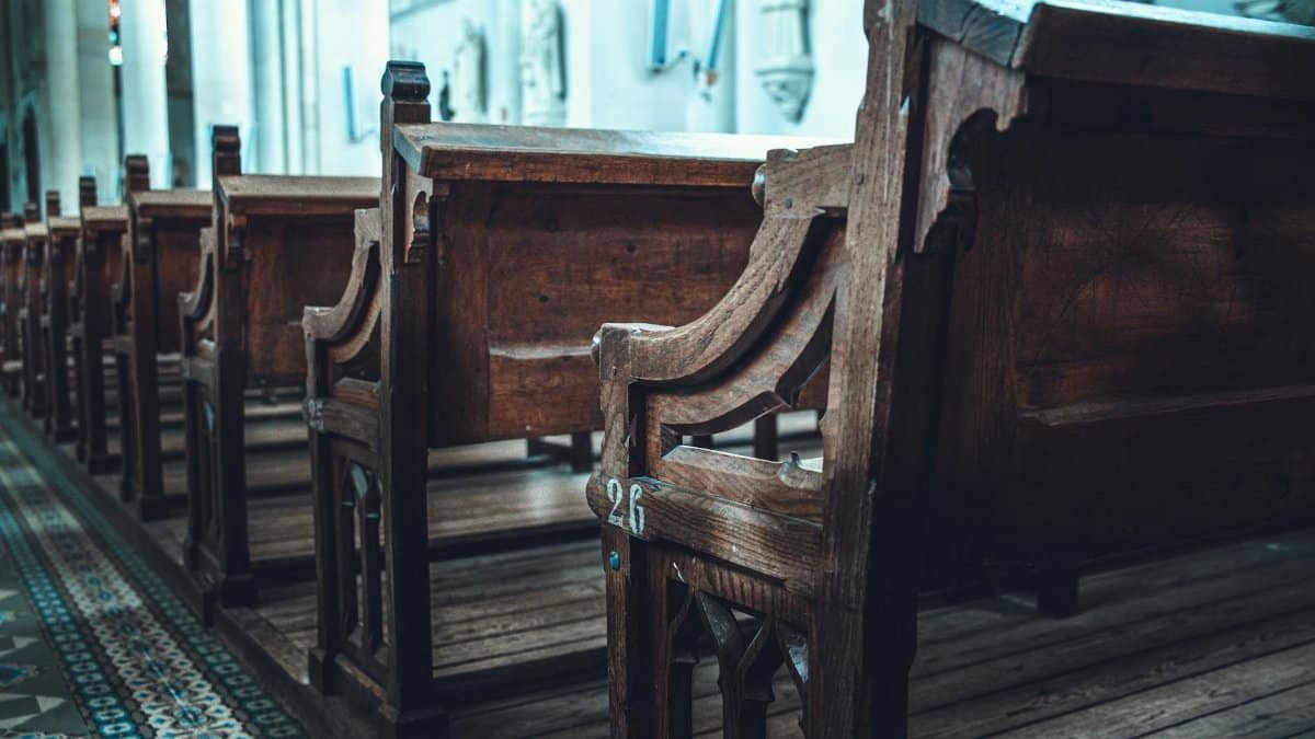 A serene view of traditional wooden church pews aligned in a sunlit interior.