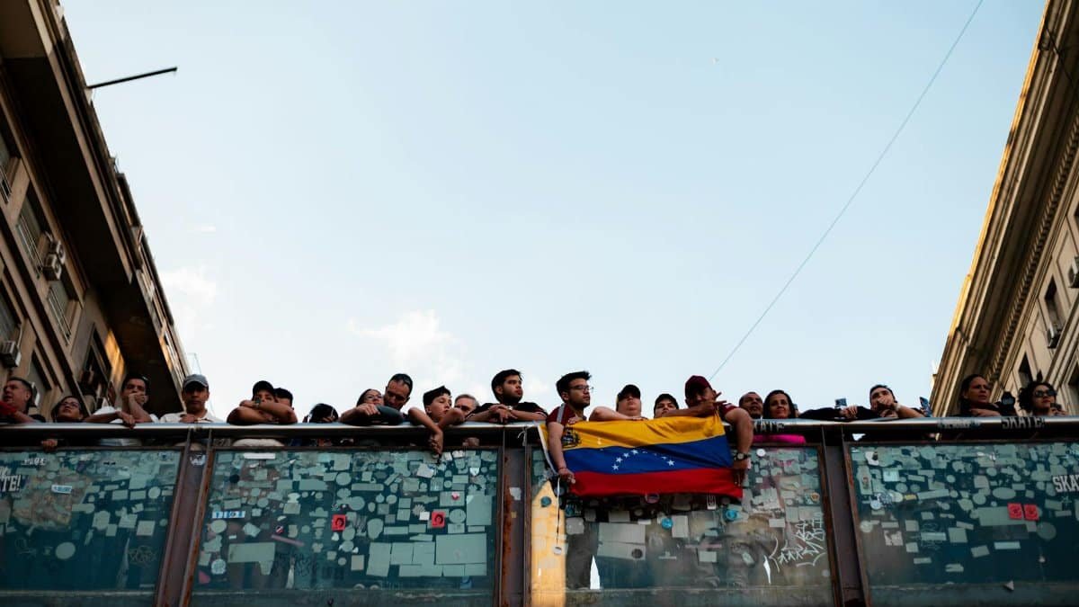 A public gathering in Buenos Aires with people holding a Venezuelan flag, symbolizing unity and hope.