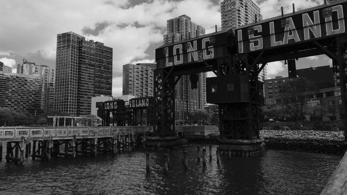 Dramatic black and white view of Long Island City waterfront with iconic signage.