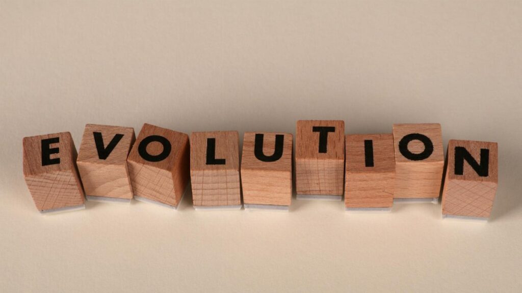 Wooden blocks spelling 'Evolution' on a neutral beige background, symbolizing change and growth.