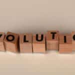Wooden blocks spelling 'Evolution' on a neutral beige background, symbolizing change and growth.