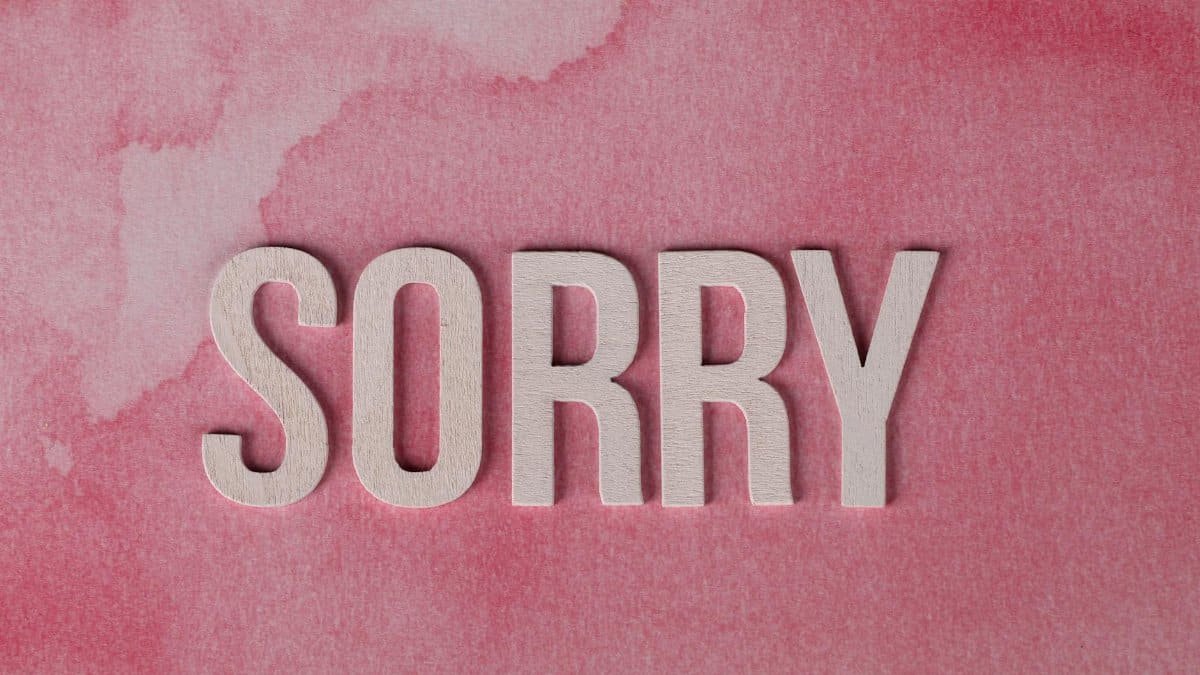 The word 'Sorry' displayed on a pink watercolor textured background, expressing an apology.
