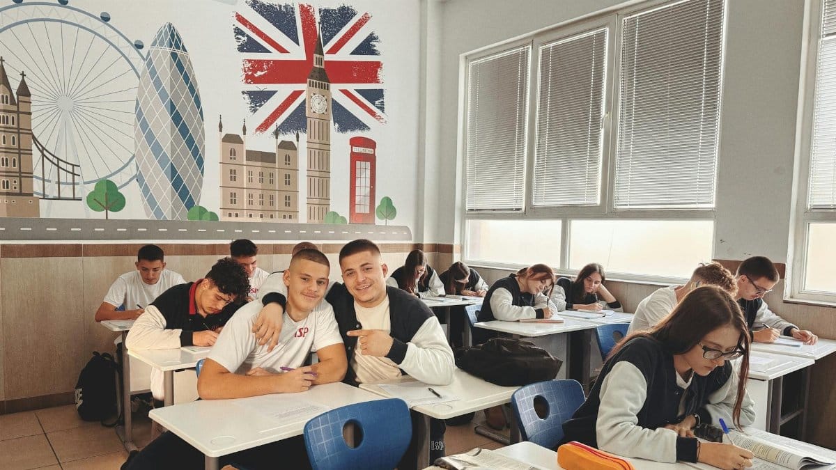 Students studying in a classroom featuring a mural of London landmarks and British flag.
