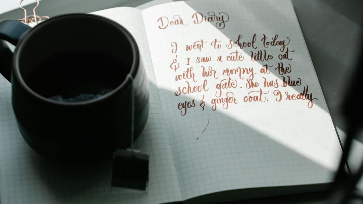 A handwritten journal entry beside a cup of tea on a sunny day.