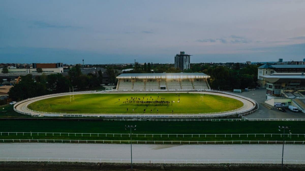High-angle shot of a sports stadium in Budapest at dusk with stadium lights on, capturing an outdoor sports scene.